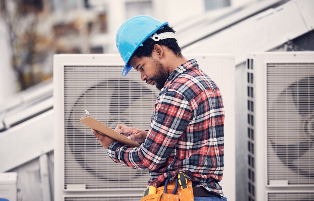 Man looking at his clipboard with ac units around him